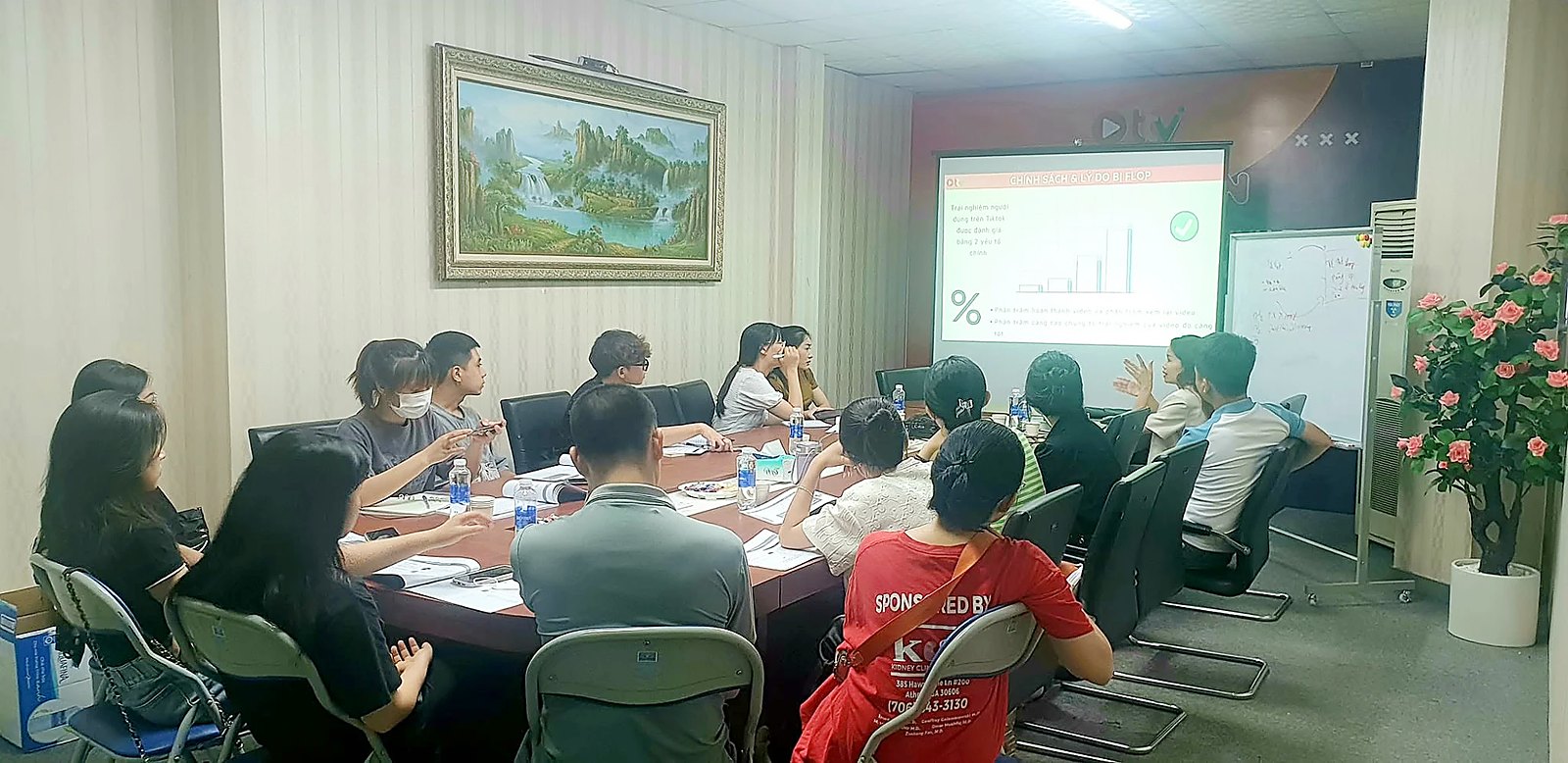 Buổi đào tạo về kênh TikTok, học viên ngồi quanh bàn họp nhìn lên màn chiếu